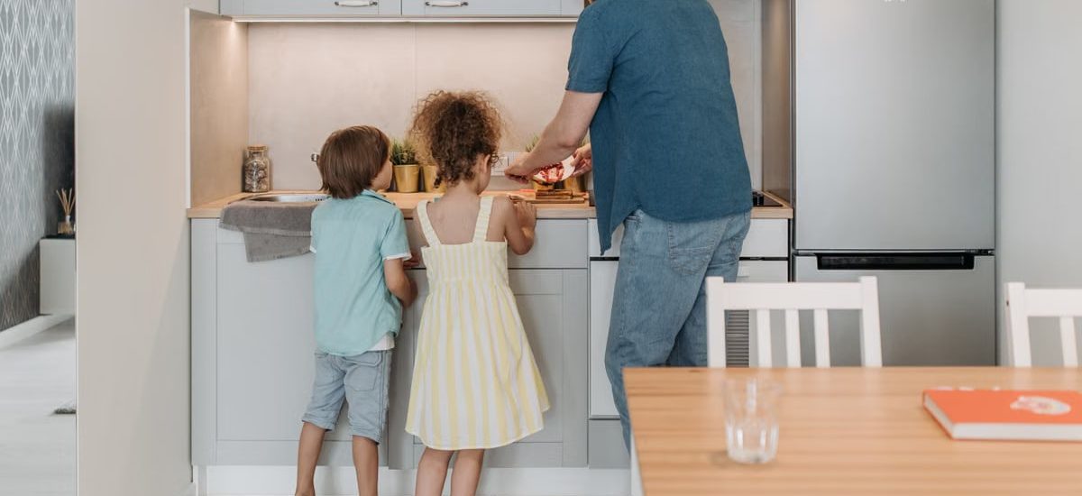 Father and children cooking together in a modern kitchen, enjoying family time.