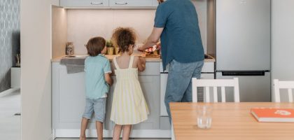 Father and children cooking together in a modern kitchen, enjoying family time.