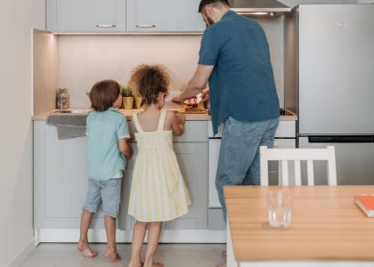 Father and children cooking together in a modern kitchen, enjoying family time.