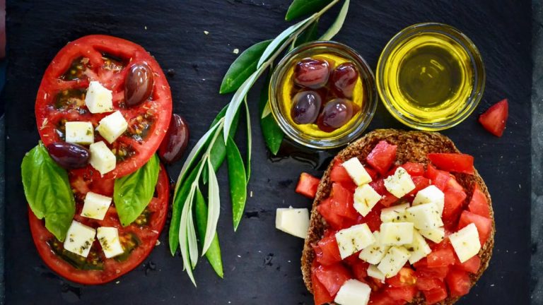 A vibrant Greek salad featuring tomatoes, feta, and olives on a slate board, perfect for healthy eating.